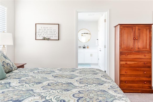 bedroom with light carpet, sink, and ensuite bathroom