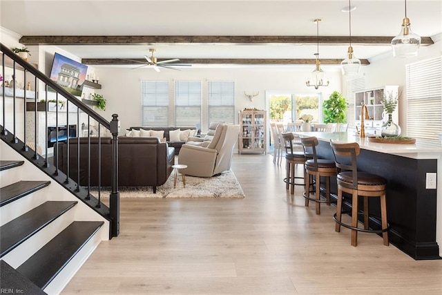 living room featuring ceiling fan, light hardwood / wood-style floors, sink, and beamed ceiling