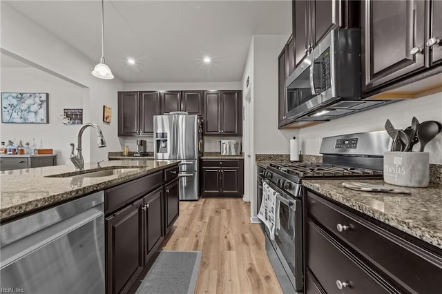 kitchen featuring dark brown cabinetry, sink, hanging light fixtures, appliances with stainless steel finishes, and light hardwood / wood-style floors