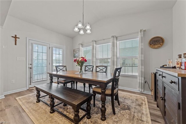 dining room with vaulted ceiling, an inviting chandelier, and light wood-type flooring