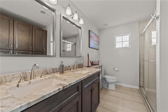 bathroom featuring vanity, toilet, and a shower with door