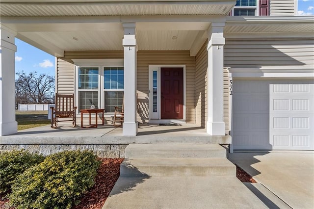 view of exterior entry featuring a garage and covered porch