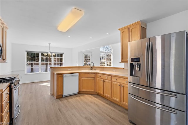 kitchen with sink, appliances with stainless steel finishes, hanging light fixtures, light hardwood / wood-style floors, and kitchen peninsula