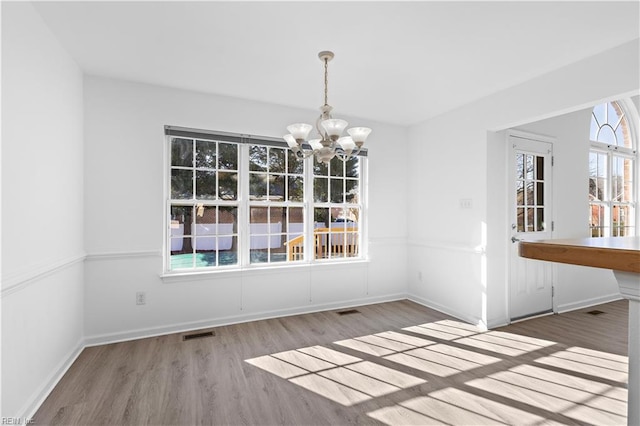 unfurnished dining area featuring a notable chandelier and light hardwood / wood-style floors