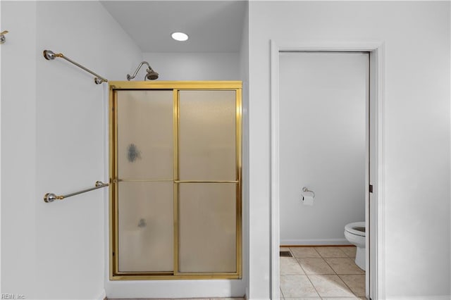 bathroom featuring a shower with door, tile patterned floors, and toilet