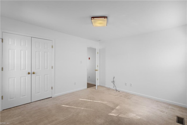 unfurnished bedroom featuring light colored carpet and a closet