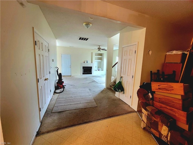 corridor featuring light carpet and a textured ceiling