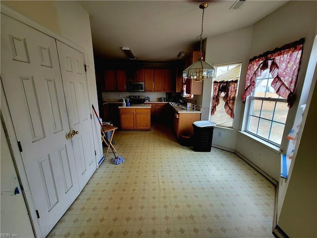 kitchen featuring an inviting chandelier, stainless steel appliances, decorative light fixtures, and sink