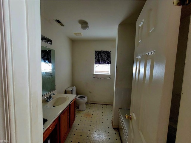 bathroom featuring vanity, a tub, and toilet