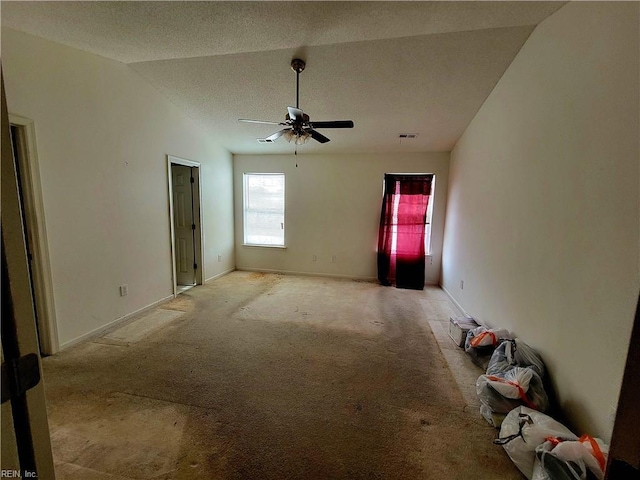 interior space with lofted ceiling, a textured ceiling, and ceiling fan