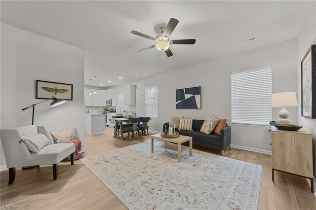 living room with ceiling fan and light wood-type flooring