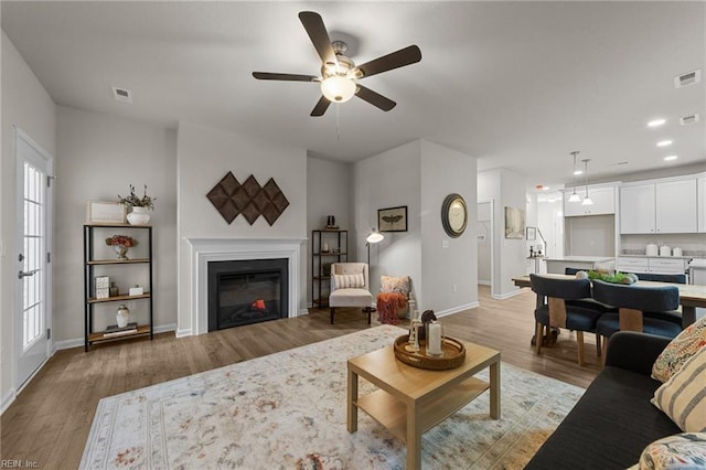 living room with plenty of natural light, ceiling fan, and light wood-type flooring