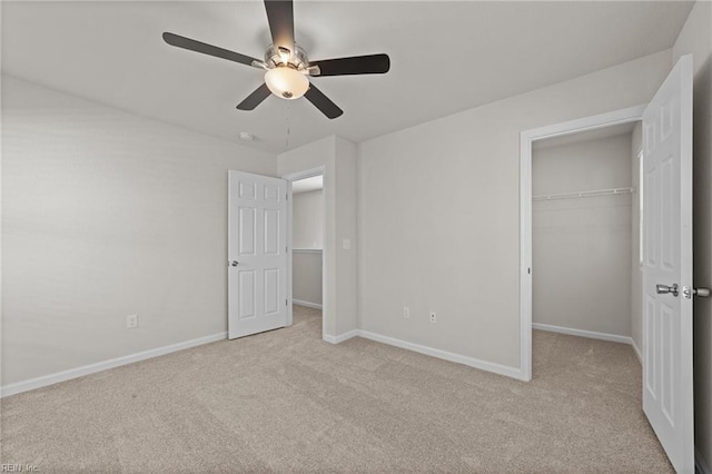 unfurnished bedroom featuring a spacious closet, light carpet, ceiling fan, and a closet