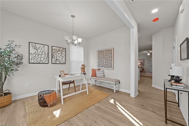 office with ceiling fan with notable chandelier and light hardwood / wood-style flooring