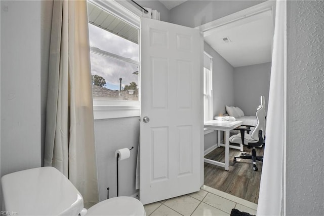 bathroom featuring plenty of natural light, toilet, and tile patterned flooring