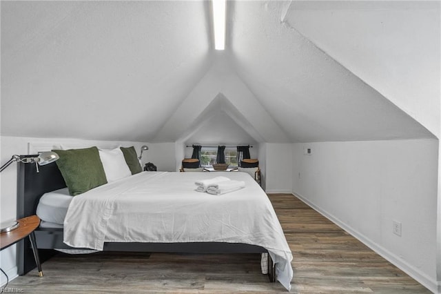 bedroom with wood-type flooring and vaulted ceiling