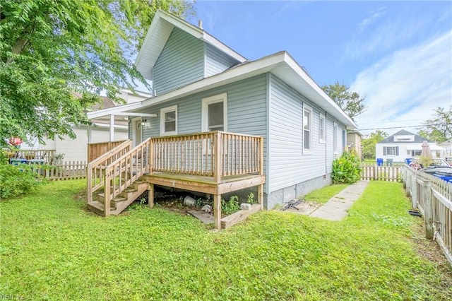 rear view of house featuring a wooden deck and a yard