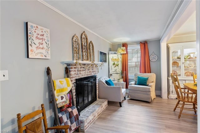 living area featuring crown molding, a fireplace, and light hardwood / wood-style flooring