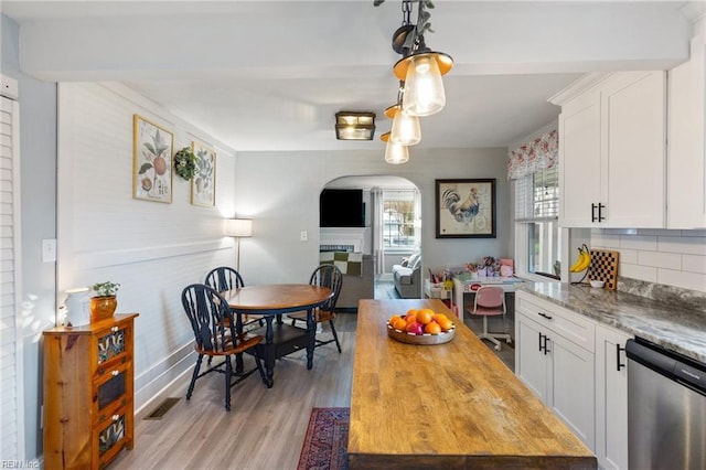 kitchen featuring white cabinetry, hanging light fixtures, light stone counters, and stainless steel dishwasher