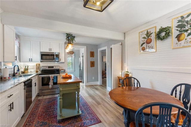 kitchen featuring sink, white cabinets, light stone counters, stainless steel appliances, and light hardwood / wood-style flooring