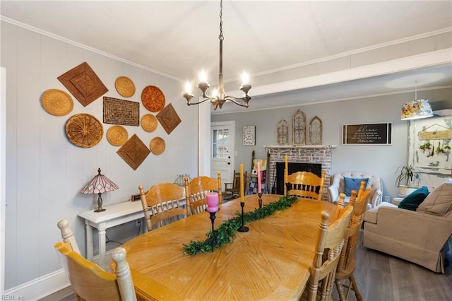 dining area with an inviting chandelier, ornamental molding, wood-type flooring, and a brick fireplace