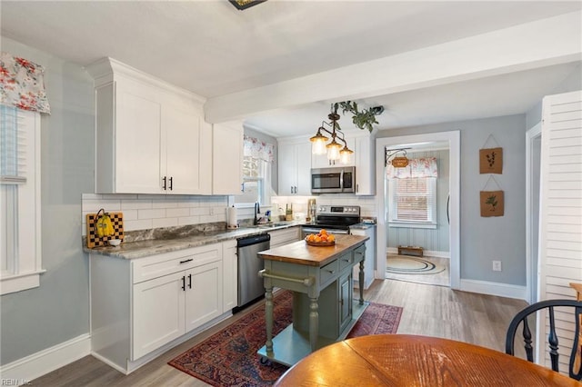 kitchen featuring white cabinetry, stainless steel appliances, light hardwood / wood-style floors, and a kitchen island