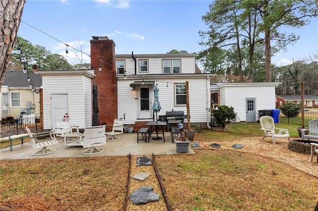 back of house featuring an outdoor fire pit, a patio, and a lawn