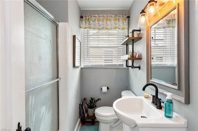 bathroom featuring toilet, a healthy amount of sunlight, sink, and a shower with shower door