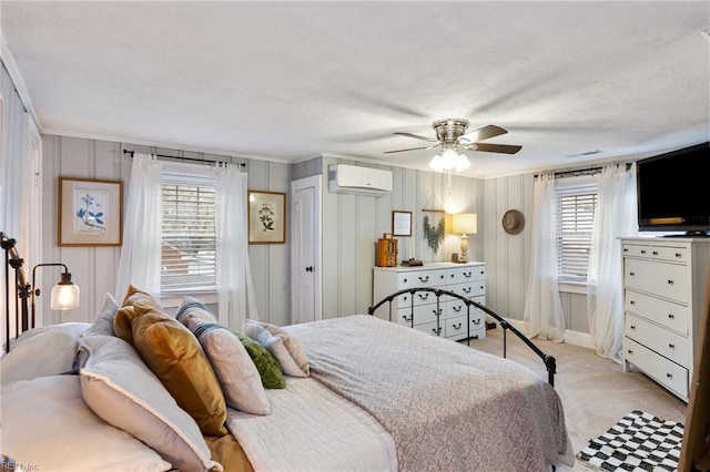 carpeted bedroom with multiple windows, ceiling fan, crown molding, and a wall mounted AC