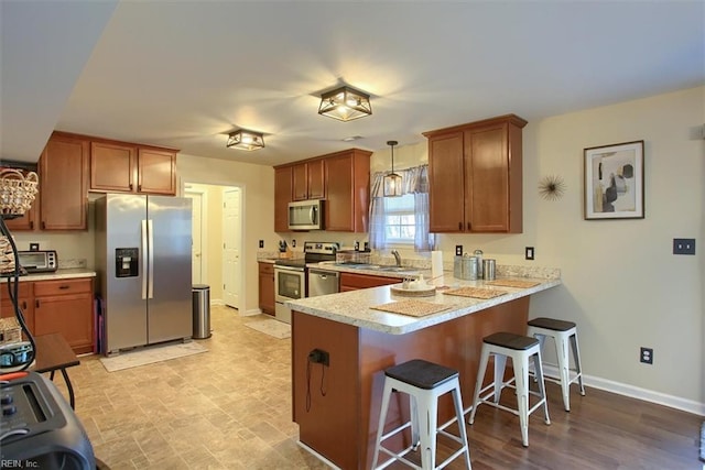 kitchen with pendant lighting, sink, a kitchen breakfast bar, stainless steel appliances, and kitchen peninsula