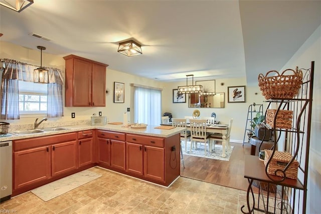 kitchen with sink, decorative light fixtures, kitchen peninsula, and dishwasher