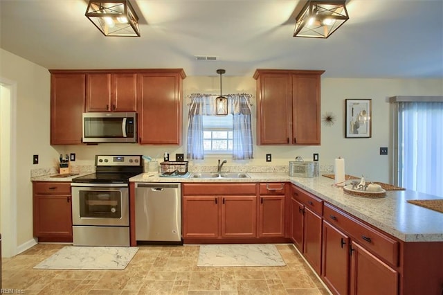 kitchen with sink, light stone counters, hanging light fixtures, kitchen peninsula, and stainless steel appliances