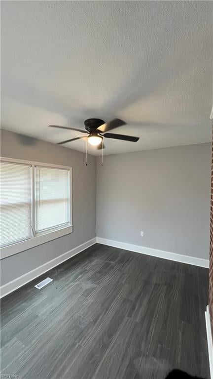 spare room with dark wood-type flooring, ceiling fan, and a textured ceiling