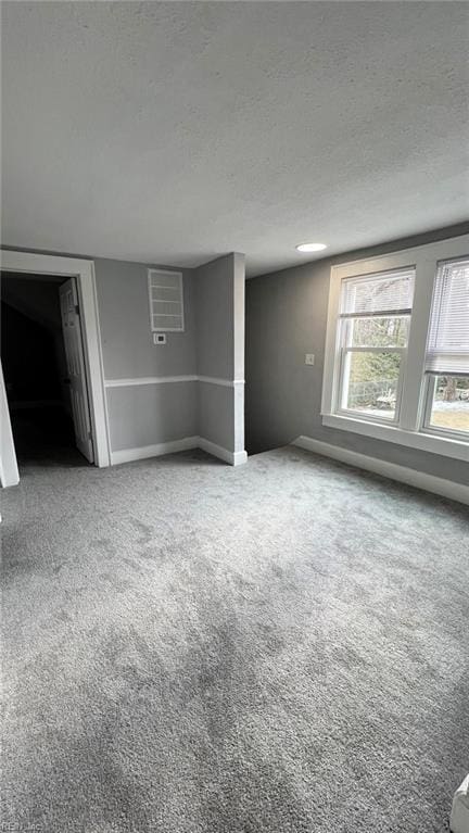 unfurnished room with carpet and a textured ceiling