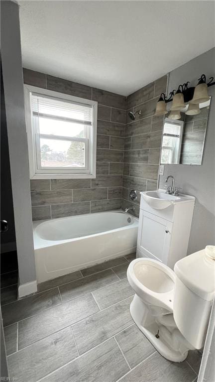 full bathroom with vanity, tiled shower / bath combo, and toilet