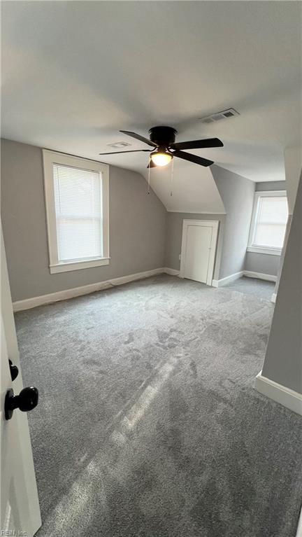 additional living space with vaulted ceiling, carpet floors, and ceiling fan