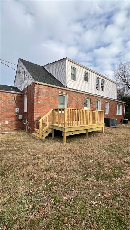 rear view of house with a wooden deck, a yard, and central AC unit