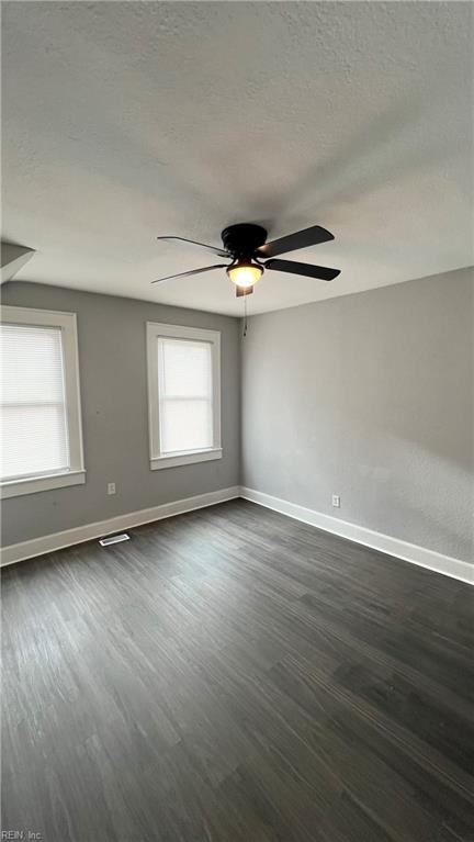 unfurnished room with a textured ceiling, dark hardwood / wood-style floors, and a healthy amount of sunlight