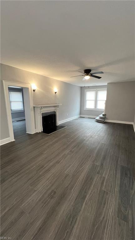 unfurnished living room featuring dark wood-type flooring and ceiling fan