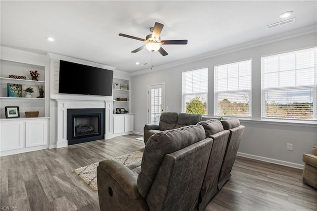 living room featuring plenty of natural light, ornamental molding, and wood-type flooring