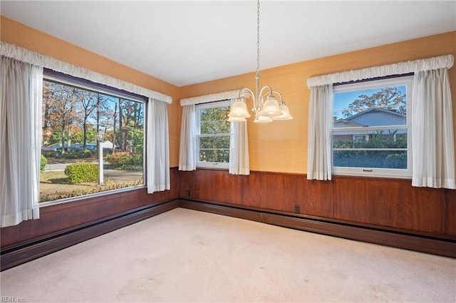 unfurnished dining area with carpet flooring, a baseboard radiator, an inviting chandelier, and wood walls