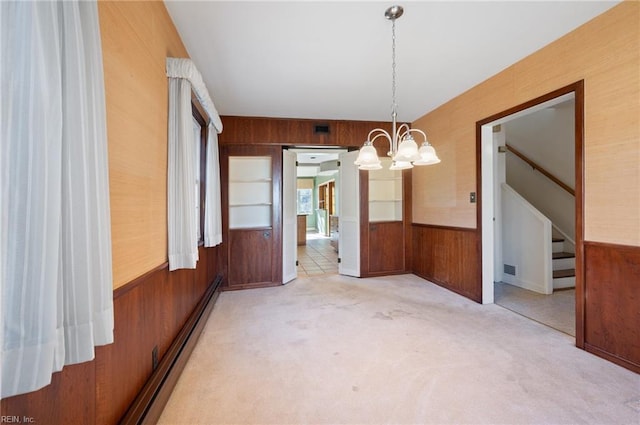 unfurnished dining area featuring a baseboard heating unit, wooden walls, light colored carpet, and a chandelier