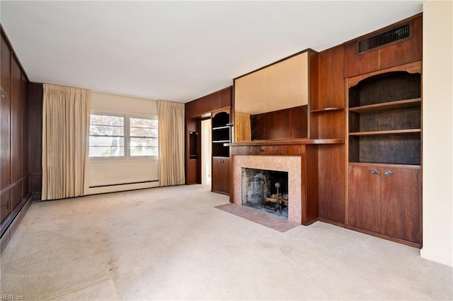 unfurnished living room with light carpet, a fireplace, baseboard heating, and wood walls