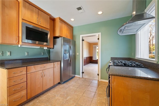 kitchen with stainless steel appliances, extractor fan, dark stone counters, and a wealth of natural light