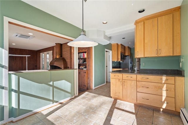 kitchen with a baseboard radiator, stainless steel appliances, hanging light fixtures, and light brown cabinets