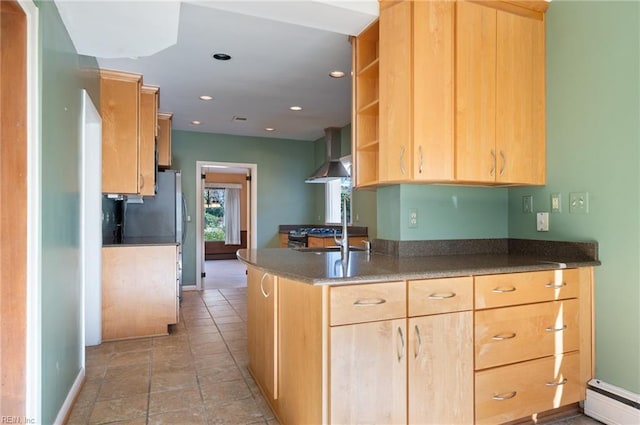 kitchen featuring stainless steel fridge, light brown cabinets, a baseboard heating unit, kitchen peninsula, and wall chimney range hood