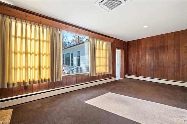 spare room featuring wood walls, carpet flooring, and a baseboard heating unit