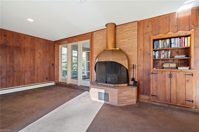 carpeted living room with a baseboard heating unit, wooden walls, and a wood stove