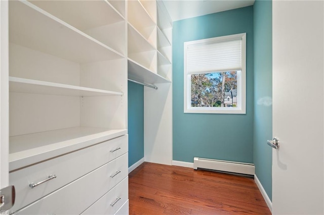 spacious closet featuring wood-type flooring and a baseboard heating unit