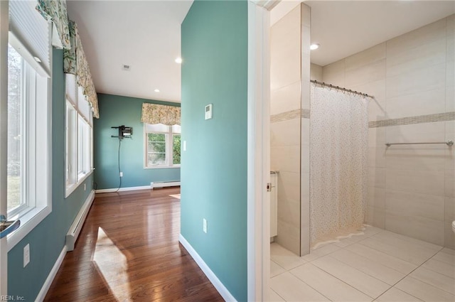 bathroom with hardwood / wood-style flooring, baseboard heating, and a shower with curtain